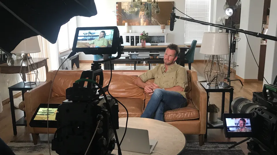 Interview being filmed in a living room set with cameras and monitors