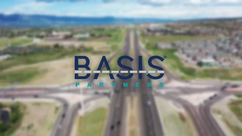 Basis Partners logo over an aerial view of a Colorado Springs highway interchange