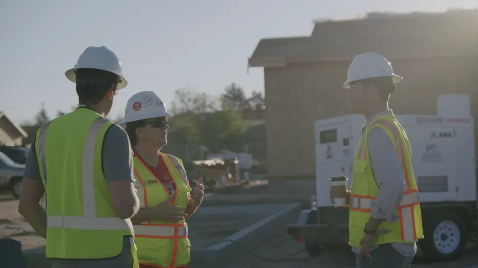 Construction crew members in hard hats and safety vests on a job site