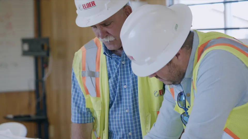 Close-up of two crew members in hard hats working on site