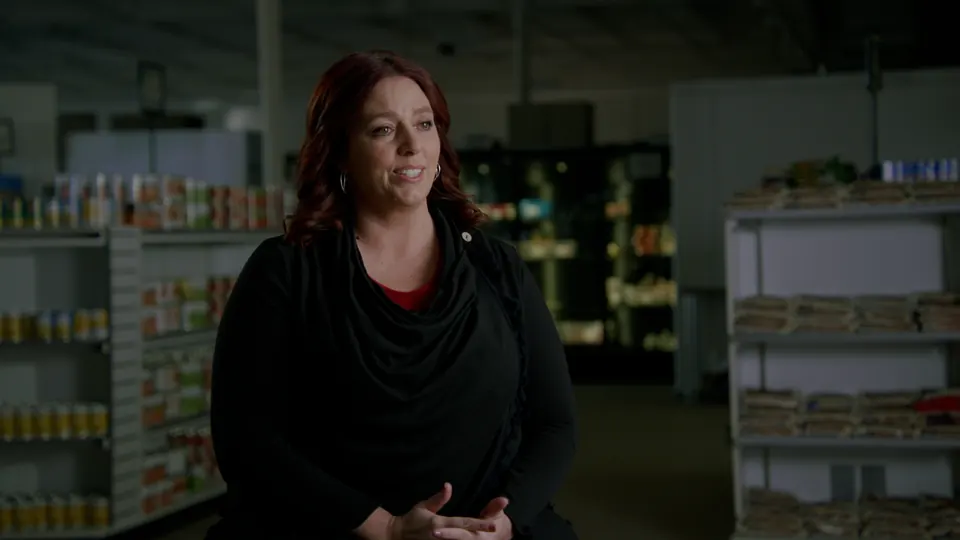 Wider frame of the same interview between the shelves