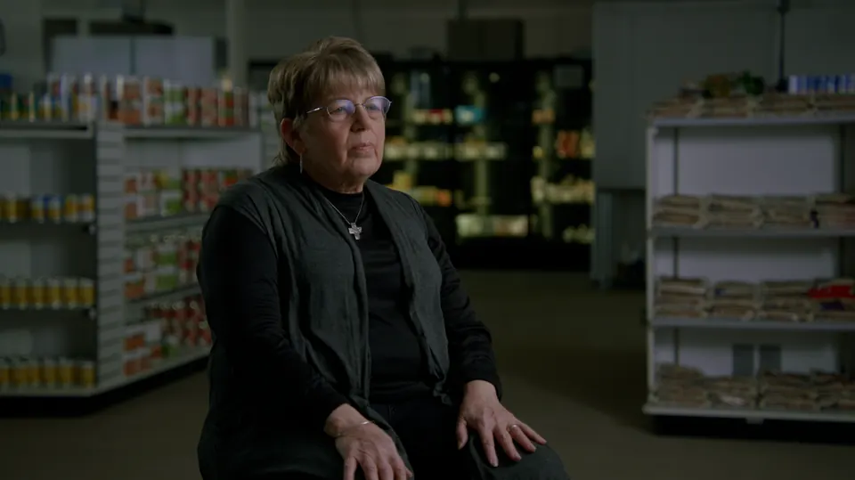 Man interviewed in a dim warehouse with shelving behind