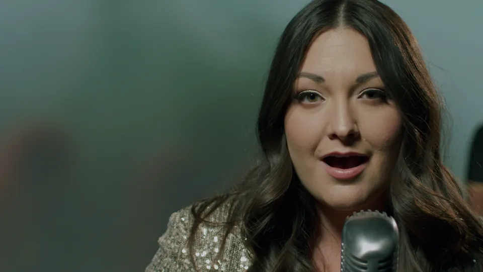 Gina Milne singing into a microphone
