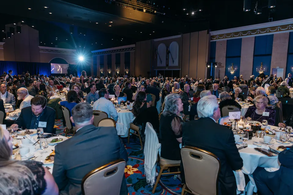 Ballroom guests seated at dinner tables facing the stage
