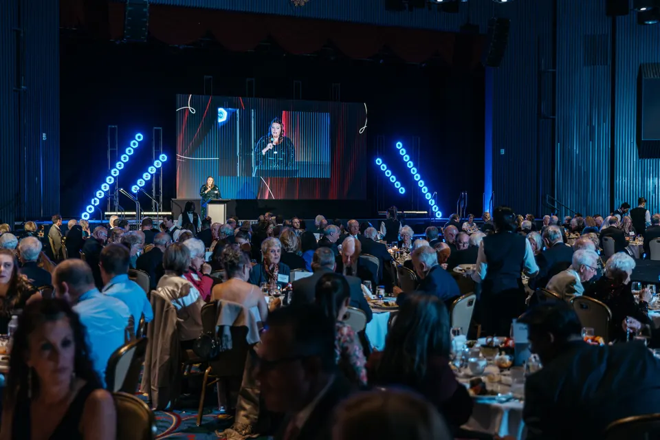 Speaker at the podium with the program on the screen behind