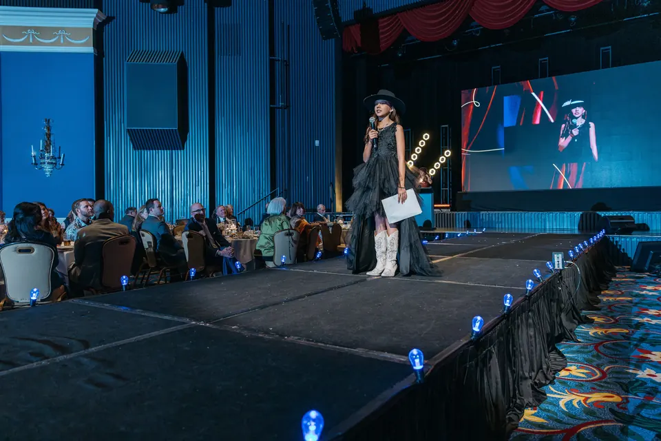 Runway and stage with blue uplighting and a large screen