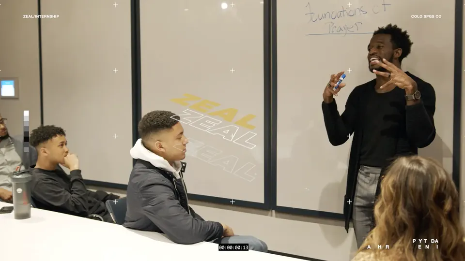 Speaker teaching a small group in a classroom, from the Zeal internship promo